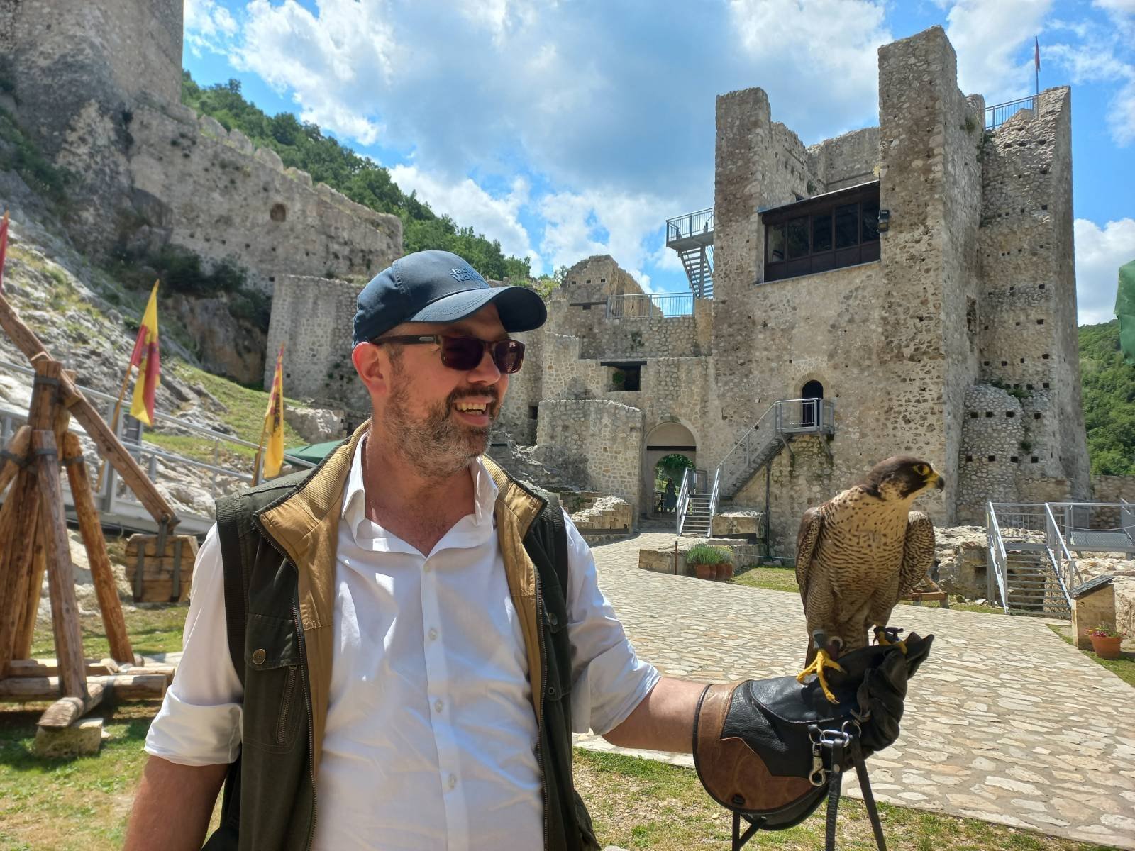 Konstantin beside a historic fortress, holding a falcon